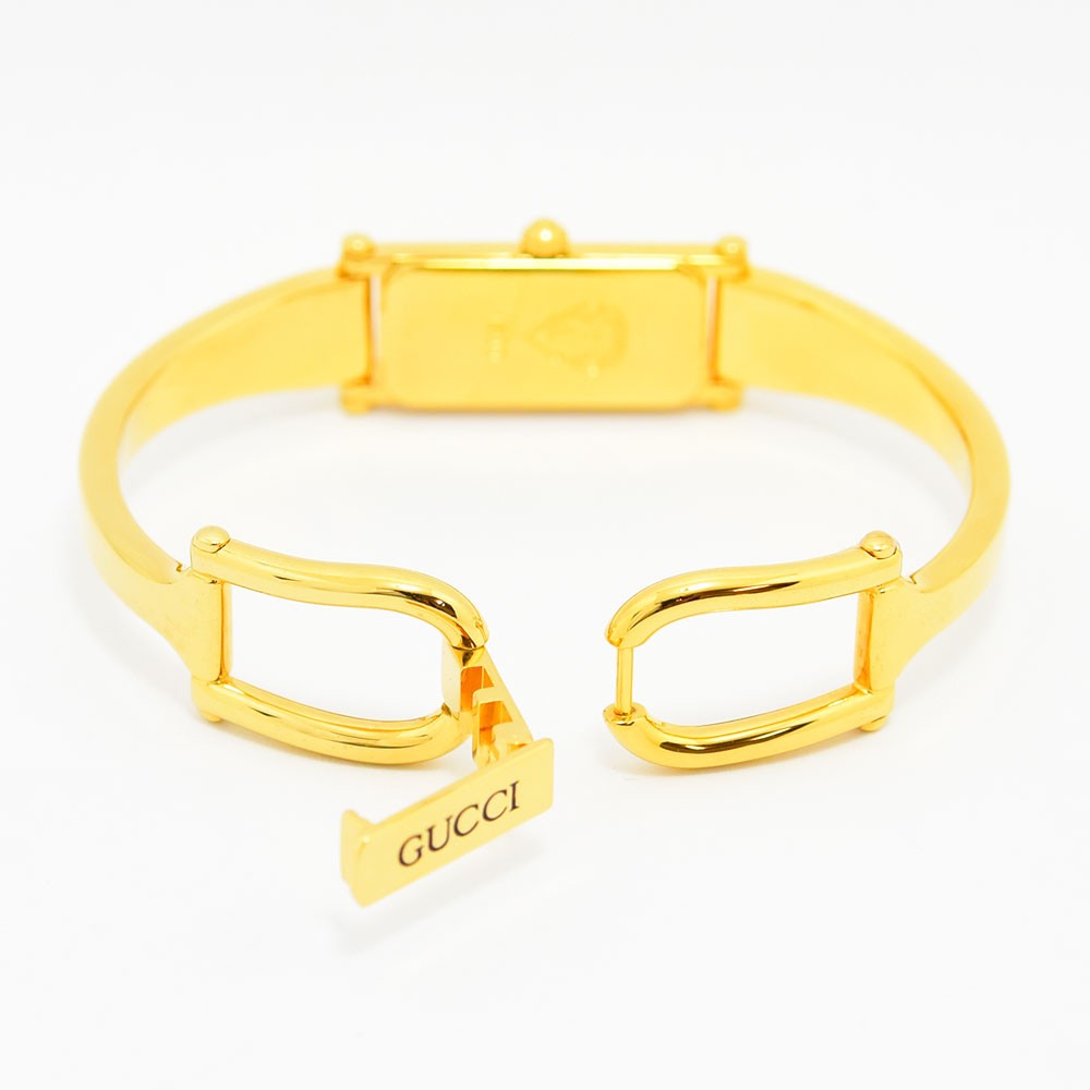 VINTAGE WATCHES FASHIONのGUCCI 1500シリーズ、ゴールドカラーのバングルウォッチ。開閉式ブレスレットの背面とロゴ刻印が見えるデザイン。