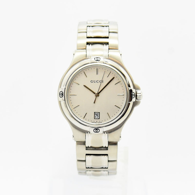 VINTAGE WATCHES FASHIONのシルバーカラーのステンレススチール製Gucciアナログ腕時計。日付表示とロゴ入りベゼルが特徴。