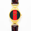 VINTAGE WATCHES FASHIONのGucciヴィンテージレディース腕時計。グリーンとレッドの文字盤、ゴールドトーンのラウンドケース、ブラウンの型押しレザーベルトが特徴。