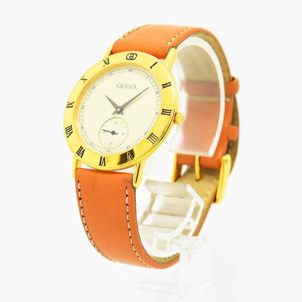 VINTAGE WATCHES FASHIONのグッチ製ヴィンテージ腕時計。ゴールドケースにオレンジのレザーベルト、ローマ数字の文字盤が特徴。