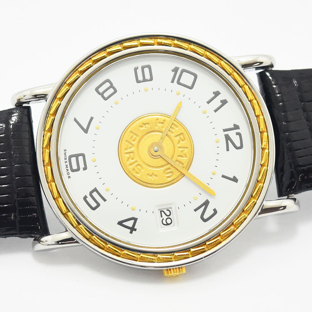 VINTAGE WATCHES FASHIONのエルメスヴィンテージクォーツ腕時計。ホワイト文字盤にゴールドのエンブレム、シルバーケース、ブラックレザーベルトの洗練されたデザイン。