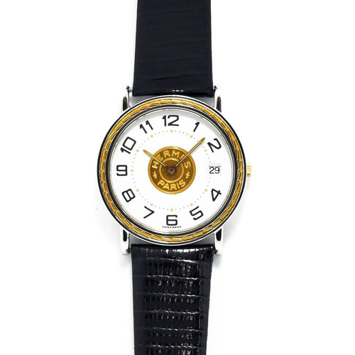 VINTAGE WATCHES FASHIONのエルメスヴィンテージクォーツ腕時計。シルバーケースにゴールドのエンブレム、ブラックレザーベルトが特徴。