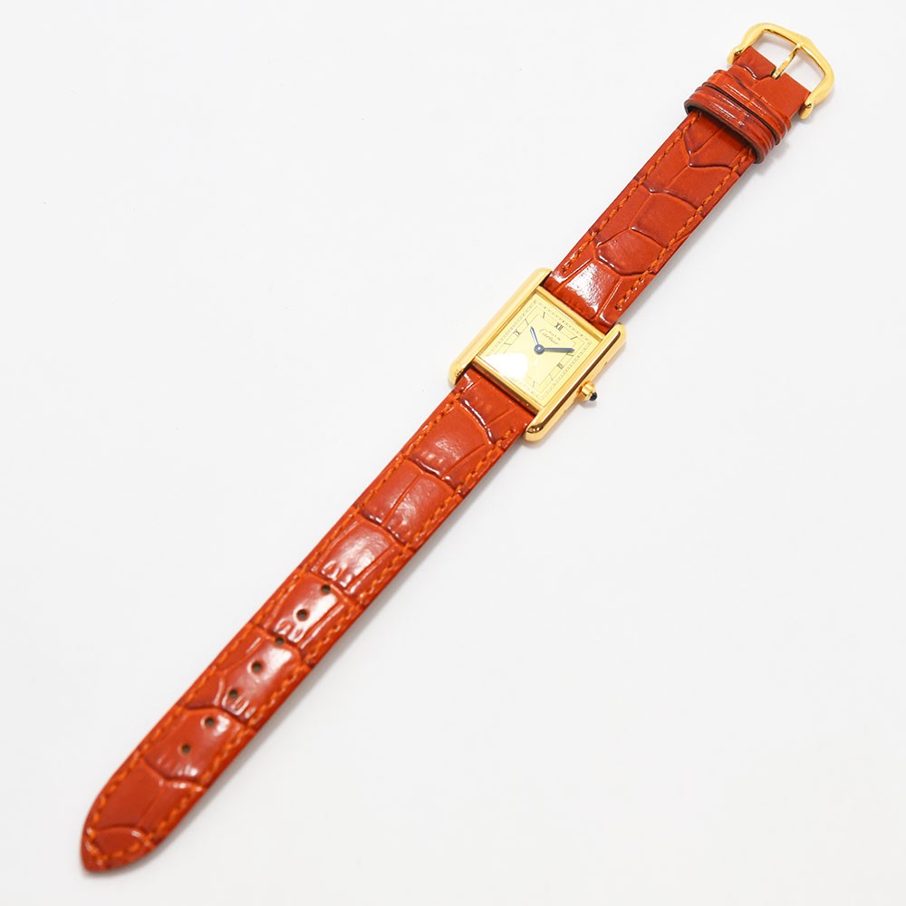 VINTAGE WATCHES FASHIONのMust de Cartier Tankウォッチ。ゴールドトーンのケース、クリーム色の文字盤、ローマ数字、オレンジのアリゲーター型押しレザーストラップ。
